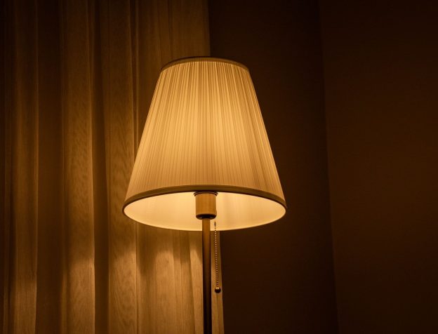 Góc phòng khách nhỏ với đèn cây ánh sáng vàng bên cạnh ghế sofa