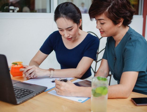 Hai người ngồi bàn cà phê trao đổi giấy tờ nhà đất