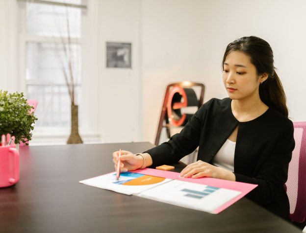 Người phụ nữ châu Á xem xét tập giấy tờ nhà đất trên bàn làm việc
