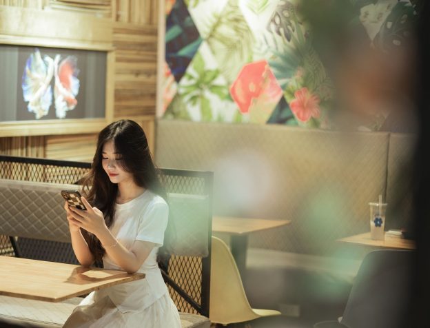 Người mua nhà xem tin rao bán trên điện thoại tại quán cà phê