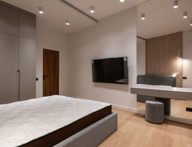 Phòng ngủ với giường lớn, tủ quần áo âm tường màu trắng và bàn trang điểm nhỏ, không gian gọn gàng