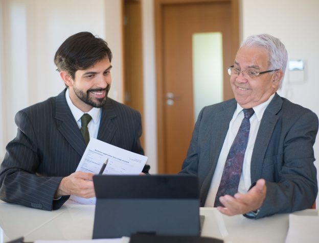 Môi giới bất động sản đang tư vấn cho khách hàng về giấy tờ pháp lý của một căn nhà, trên bàn có tài liệu