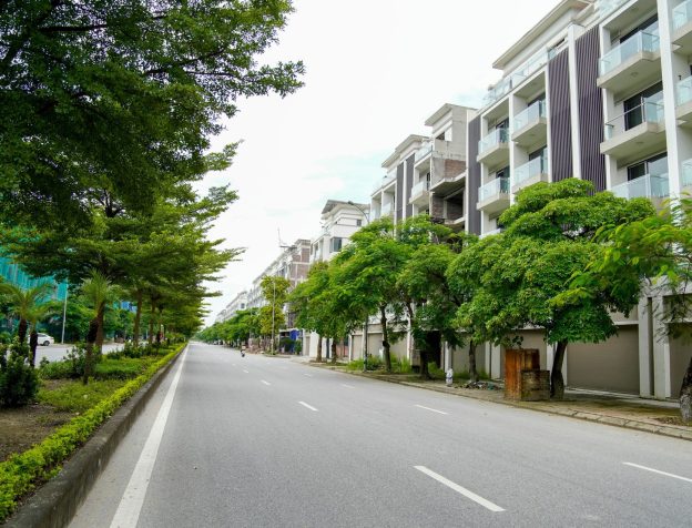 Một người đàn ông Việt Nam đang dùng máy tính bảng để tra cứu thông tin về một dự án bất động sản, phía sau là mô hình nhà ở.