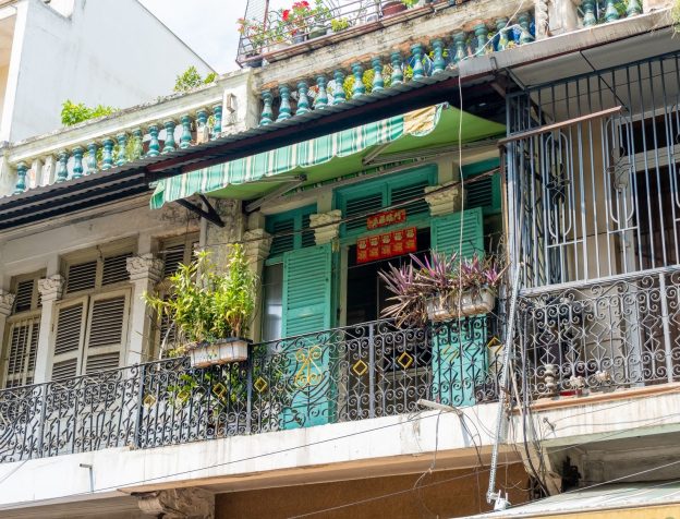 Một ngôi nhà phố Việt Nam hiện đại với mặt tiền hướng ra đường, có ban công và cây xanh nhỏ trang trí.