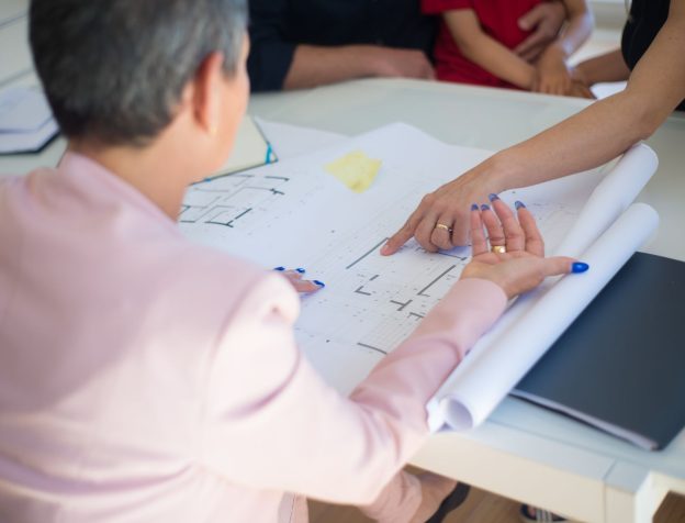 Một người đang nghiên cứu bản đồ quy hoạch đô thị và các tài liệu pháp lý liên quan đến bất động sản.