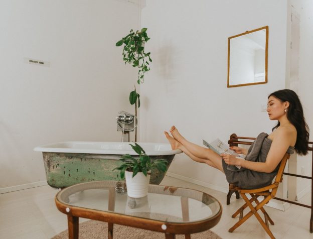 Ảnh minh họa: Góc phòng tắm được trang trí với một chậu cây xanh nhỏ, khăn tắm xếp gọn gàng và nến thơm, tạo không gian thư giãn.